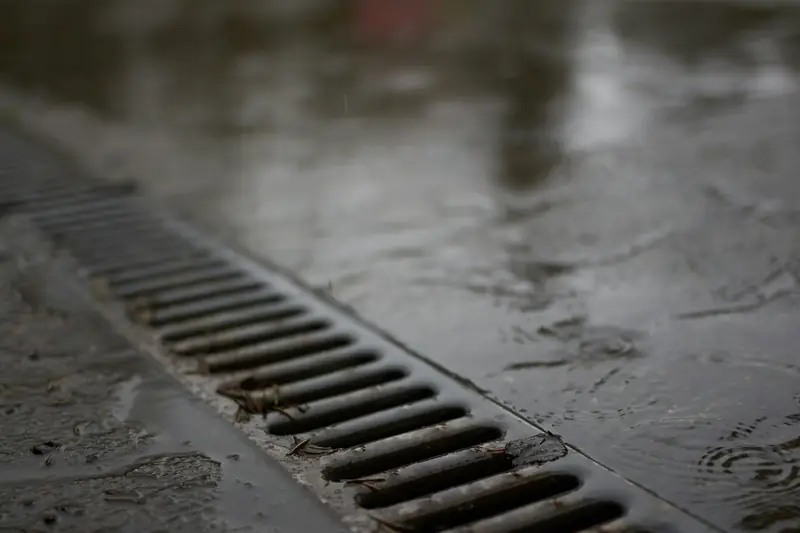 A metal drain grate on wet concrete