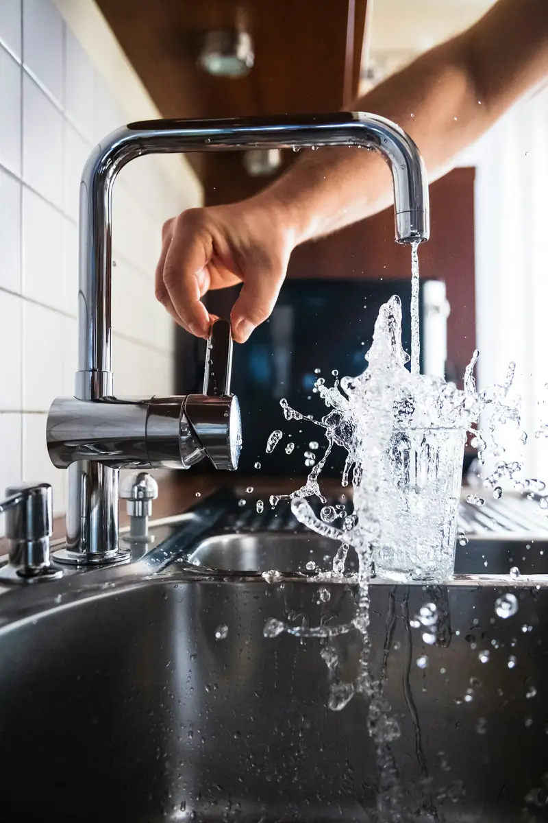 A hand opening a kitchen tap